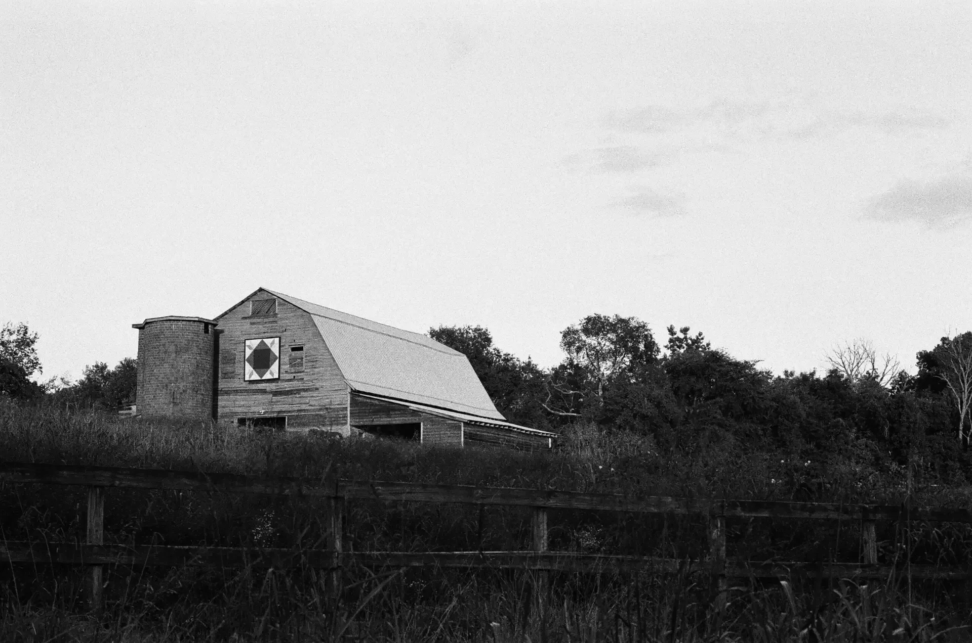 Weathered historic barn and silo behind a split-rail fence at dusk in rural Ohio