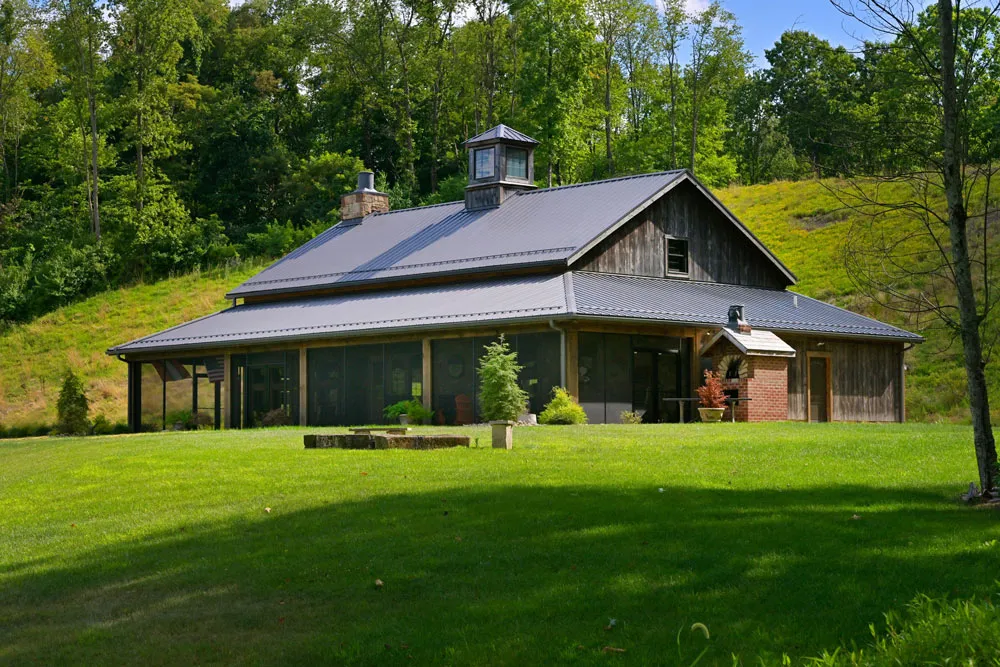 Converted timber frame party barn with dark wood siding and wraparound porch in Dover, Ohio