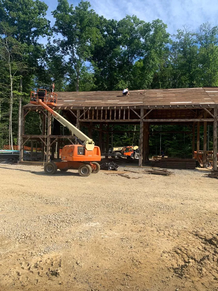 Sugarcreek Builders crew working from a boom lift on an exposed historic timber frame