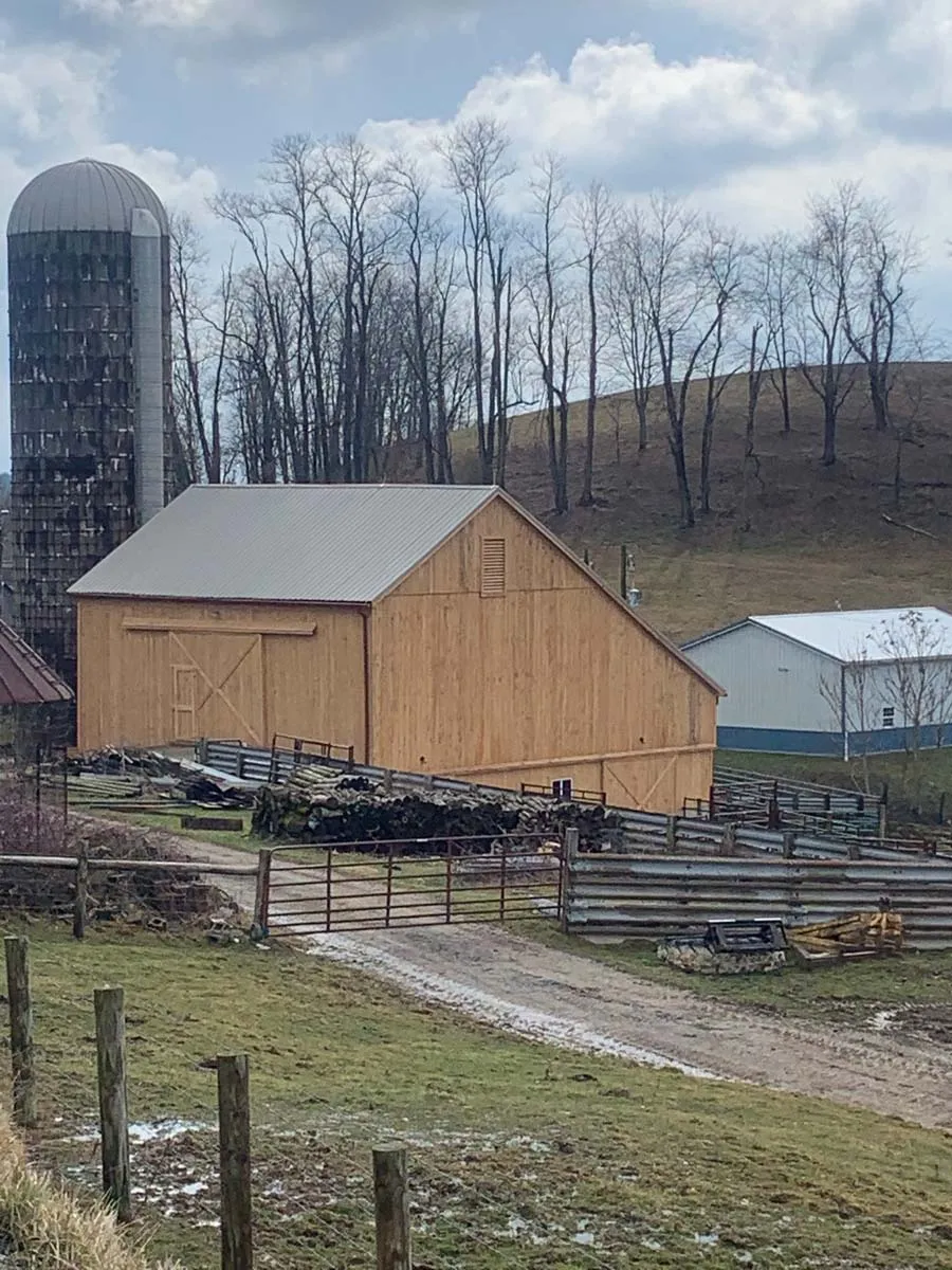 Restored bank barn with fresh hemlock siding beside a silo on a working Ohio farm