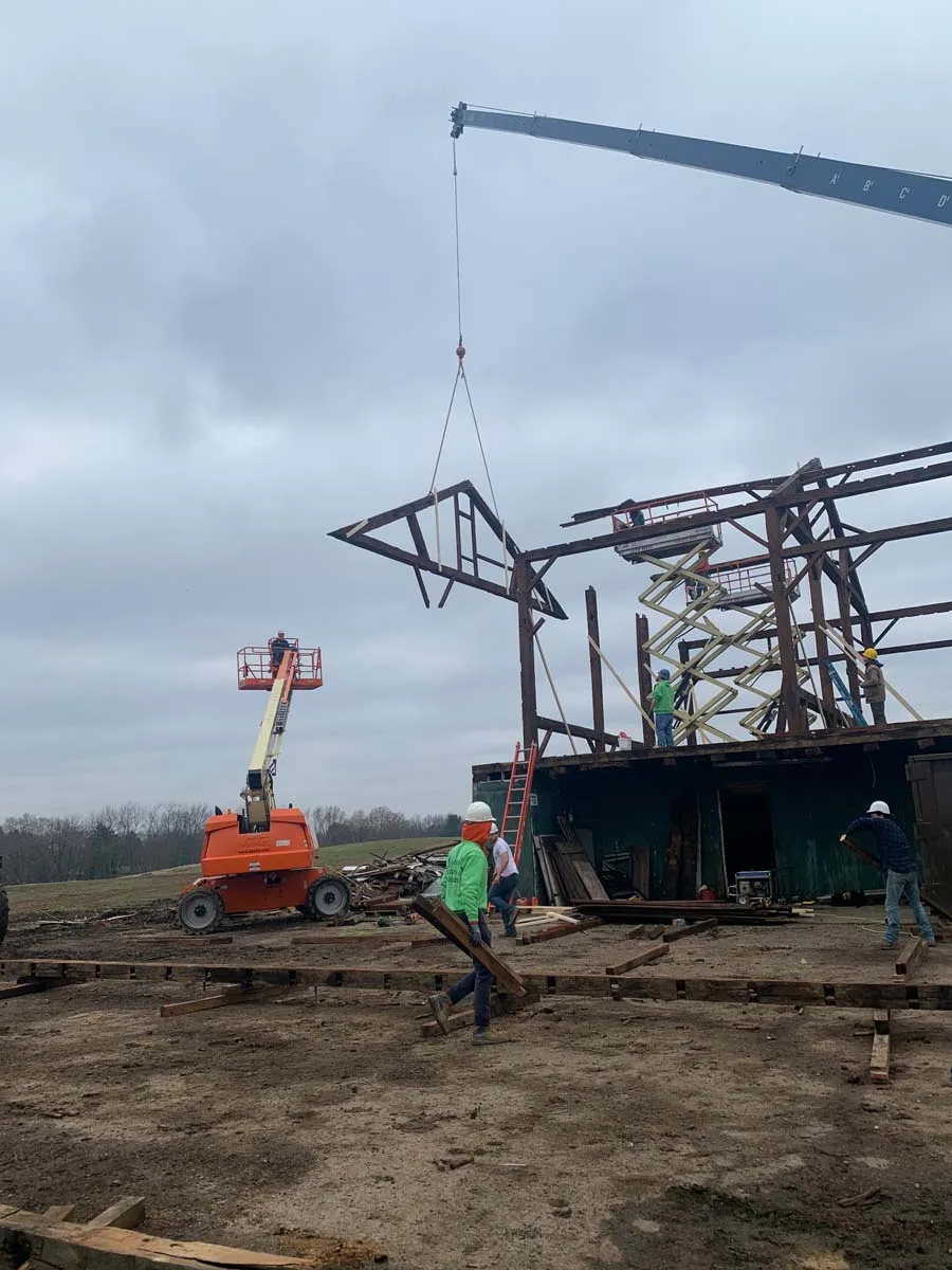 Crane lifting a timber truss while Sugarcreek Builders dismantles a historic Ohio barn